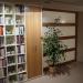 Bücher-Wohnwand mit integrieter Schiebetür in Schweizer Birnbaum und Schleiflack